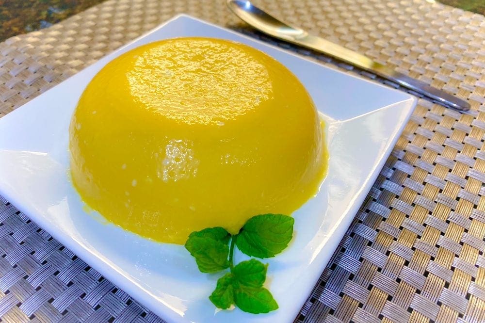 A plated mango pudding, one of the featured recipes from around the world, sits on a white plate.