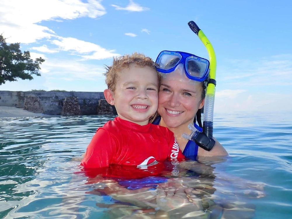 A mom wearing snorkel gear holds her young son in the water off the coast of Dry Tortugas National Park.