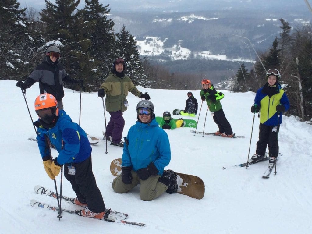 A large group of skiiers rests at the top of a run at Okemo Mountain Resort, one of the best family ski resorts in Vermont.