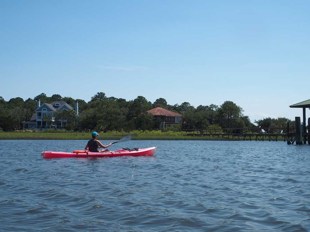 Person in red kayak in blue water in Amelia Island Florida, one of the best spring break family destinations!