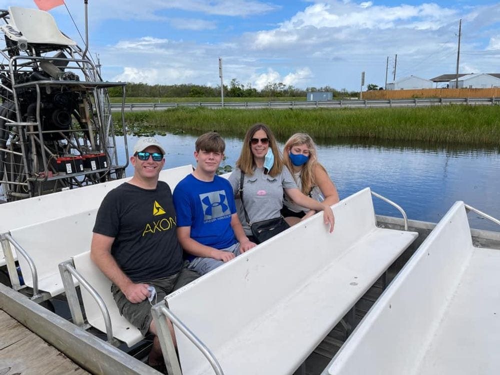 A family of four sits together on an airboat tour in Miami.