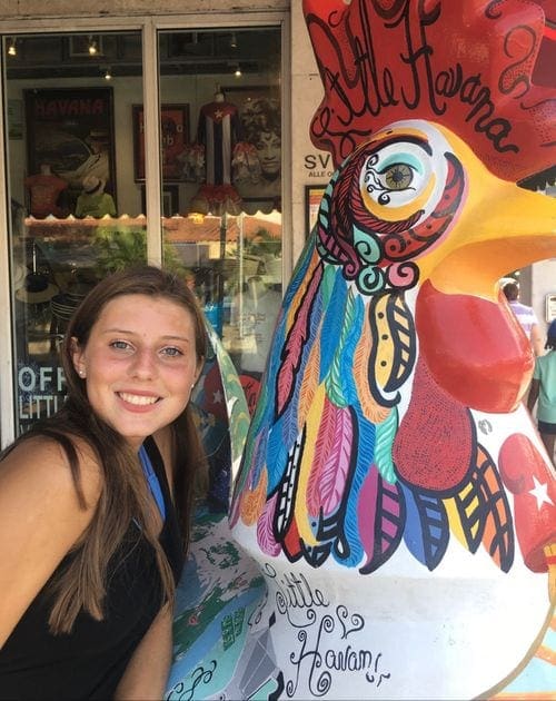 A teenage girl poses with a large rooster in Little Havanna.