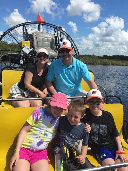 A family of five huddles for a picture in an airboat in the Everglades.