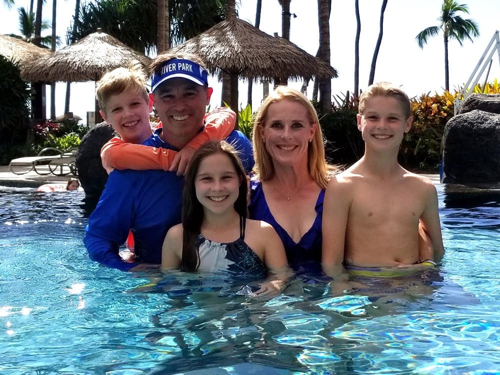 A family of five smiles while enjoying time in the pool.