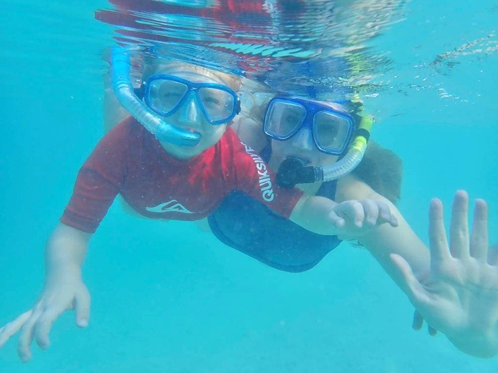 A mom and young boy wave underwater while snorkeling in Dry Tortugas National Park.