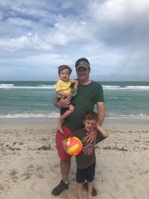 A dad and his two young boys stand on South Beach in Maimi.