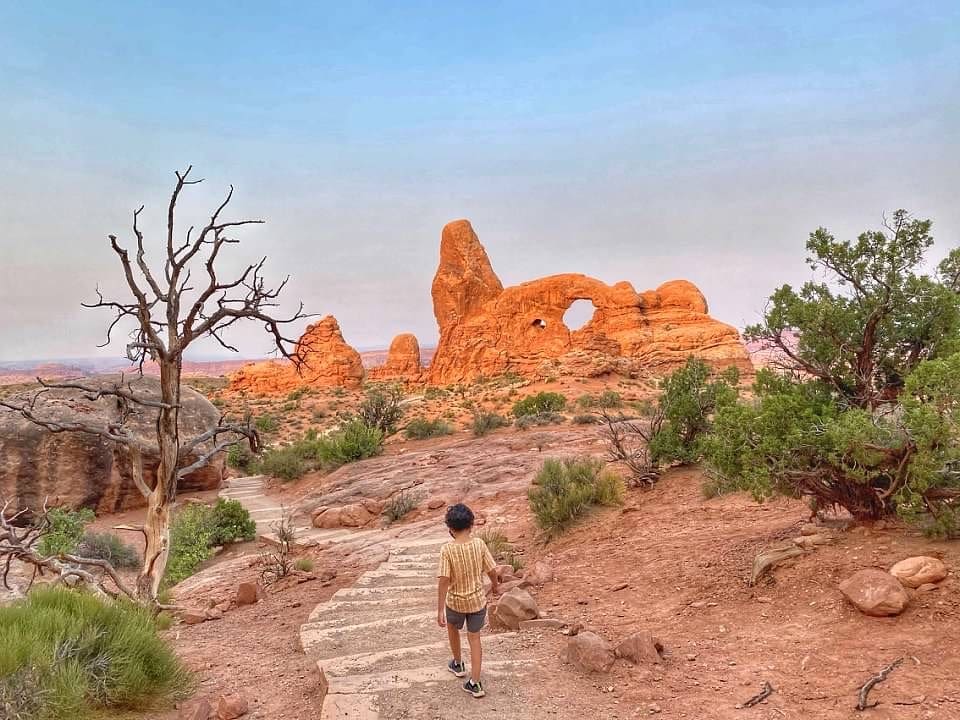 A young boy wanders a stone path in Arches National Park, a must stop on your Utah road trip itinerary!