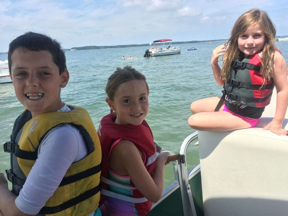 Three kids ride along in a pontoon of Rehoboth Beach, one of the best weekend getaways near Baltimore for families.