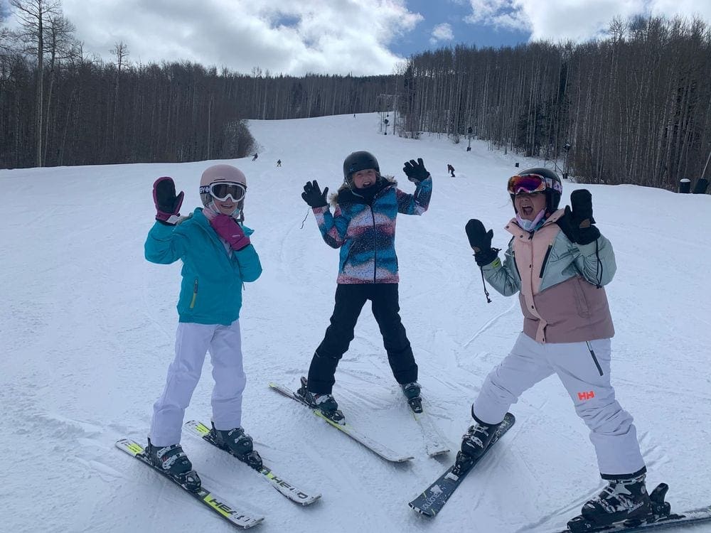Three teenagers ski at the Vail Ski Resort on an overcast day, a perfect activity when visiting Vail in the winter with kids.