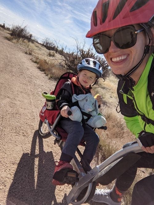 A mom smiles while posing with her young child on a tandem bike on a trail at Brown's Rnach, near Phoenix.