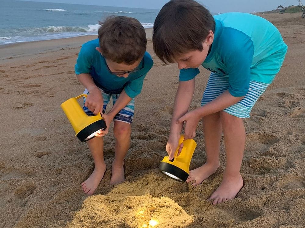 Two young boys use flashlights to look for crabs on the beach in the Outer Banks.