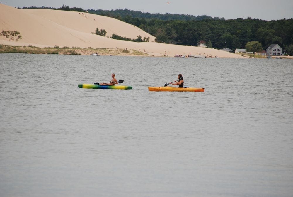 Two kayakers enjoy a nice day at Silver Lake, with the inconic sand dunes in the background.