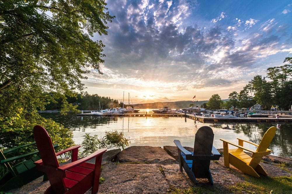 Several chairs look out onto a lake at sunset at Basin Harbor, one of the best summer lake resorts in the Northeast for families.