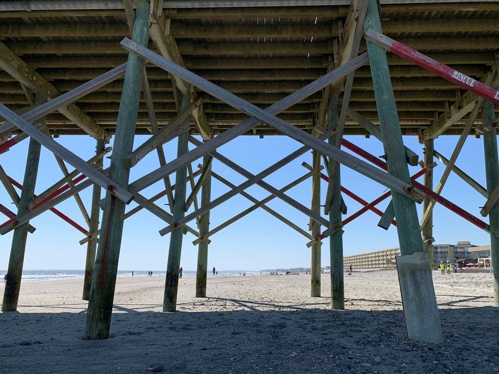 Underneath the Folley Park boardwalk, featuring sand and an ocea view near Charleston.