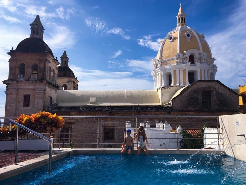 Two kids sit with their feet in a pool, while staying at the Casa Claver Boutique Hotel.