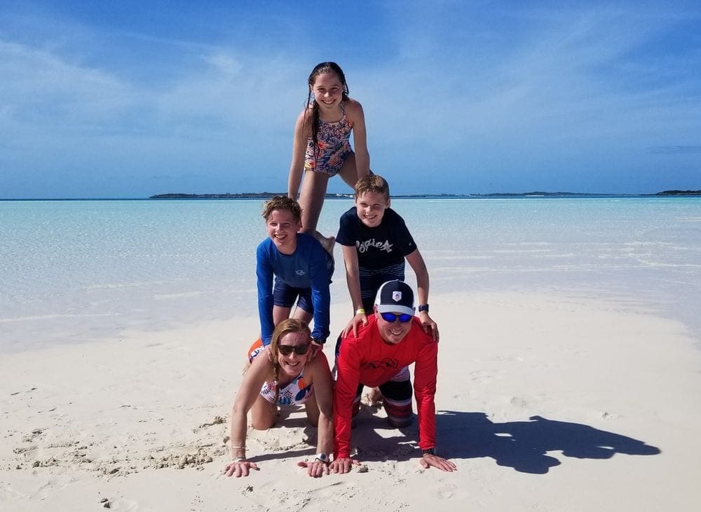 Family of 5 making a pyramid formation on a sandbar in the Bahamas.