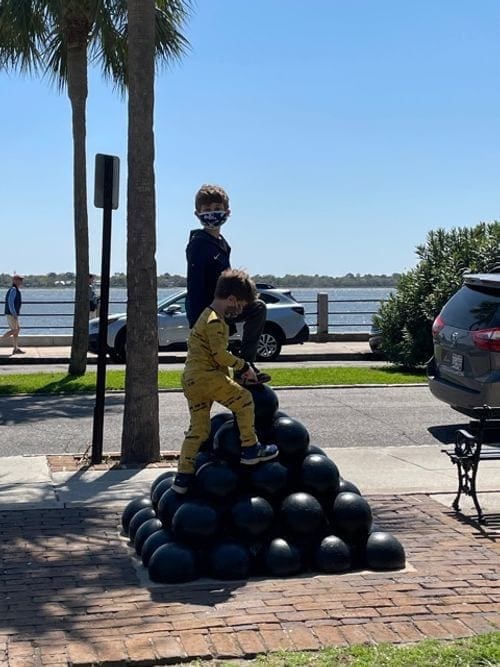 Two young boys climb a structure of cannon balls at Fort Sumter.