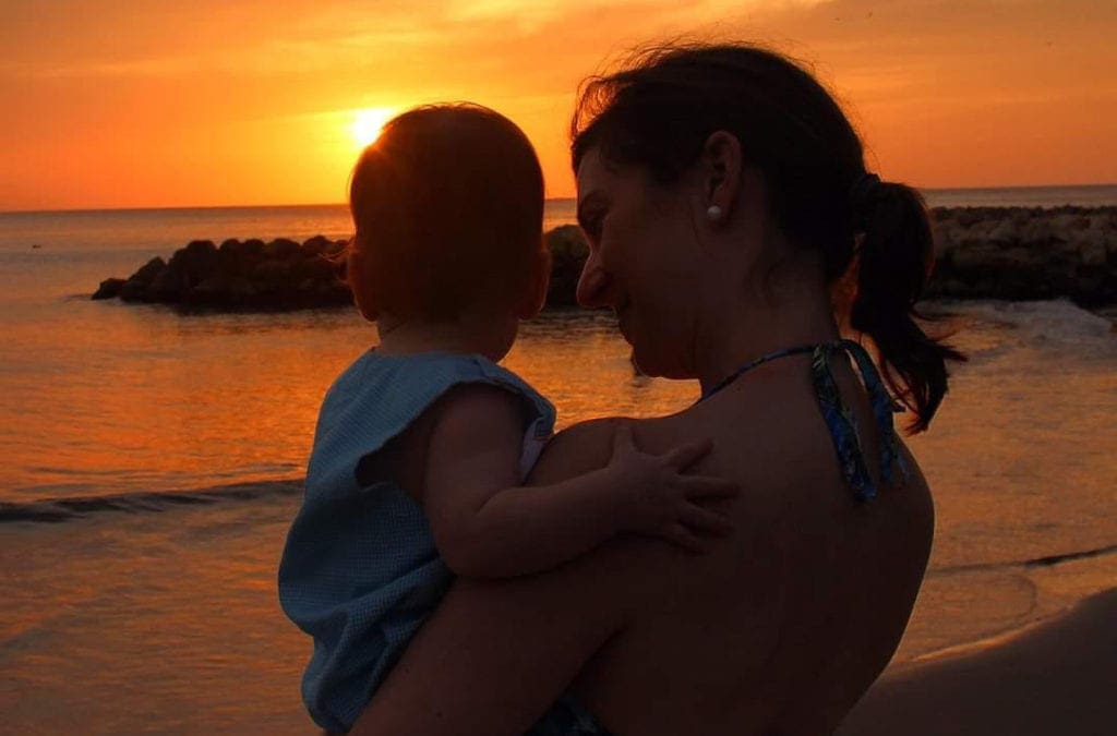 A mom holds her infant during a stunning sunset in Cartagean.