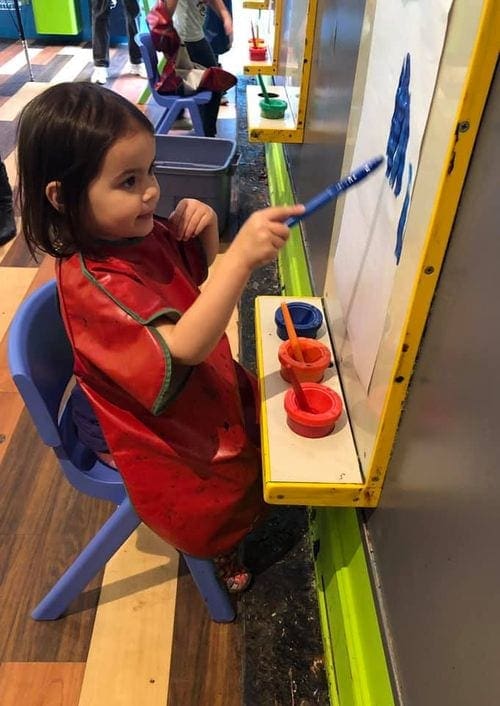 A young girl paints with blue paint at the Children's Museum in Charleston.