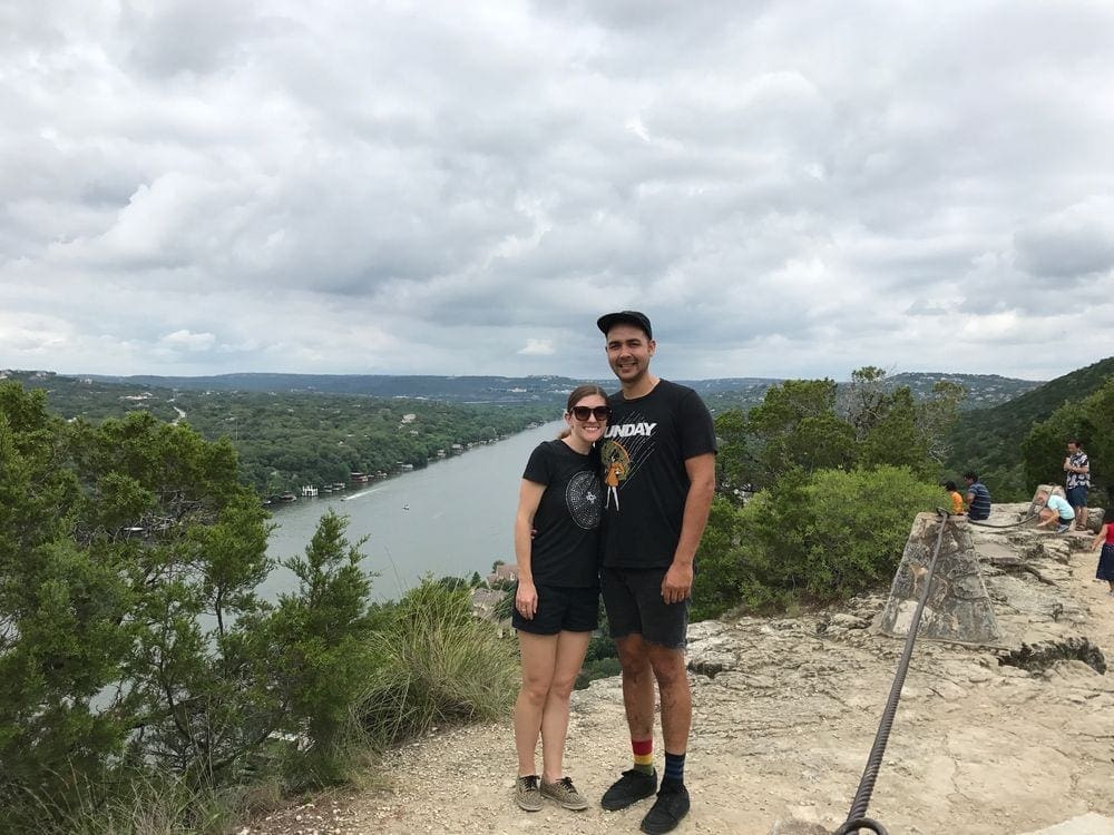 A couple stands atop Mount Bonnell while hiking near Austin.