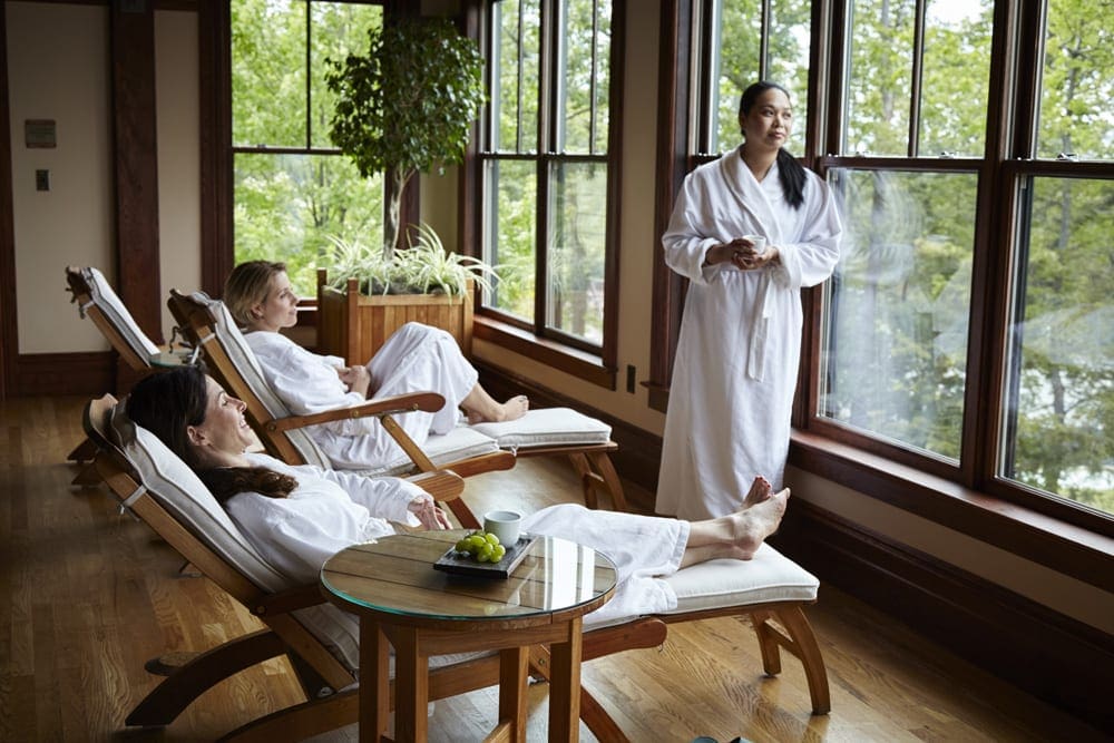 Three women in white robes enjoy a day at the spa at Mohonk Mountain House, one of the best mom's weekend getaway locations.