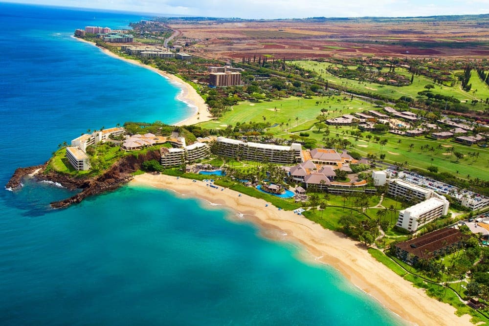 An aerial view of the Sheraton Maui Resort & Spa, one of the best family hotels in Maui, featuring their larage stretch of beach and lush, green grounds.