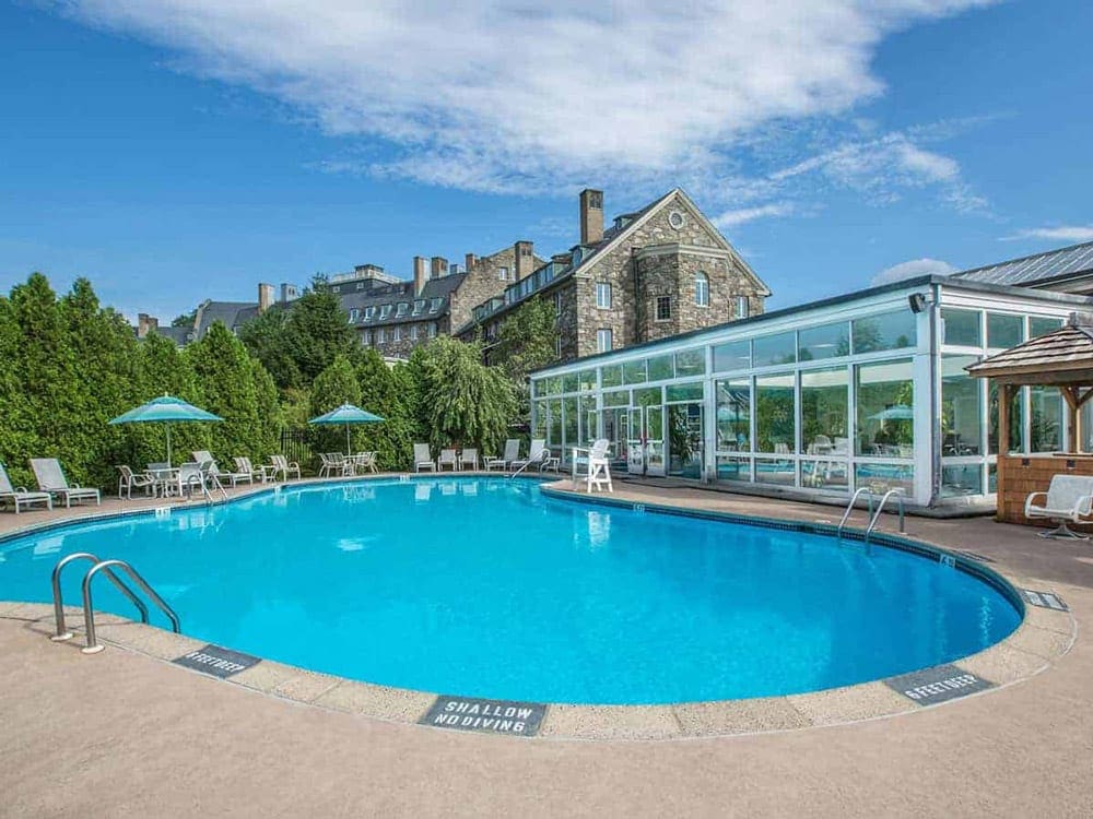 A large pool sits in front of resort buildings at Skytop Lodge, one of the best summer lake resorts in the Northeast for families.