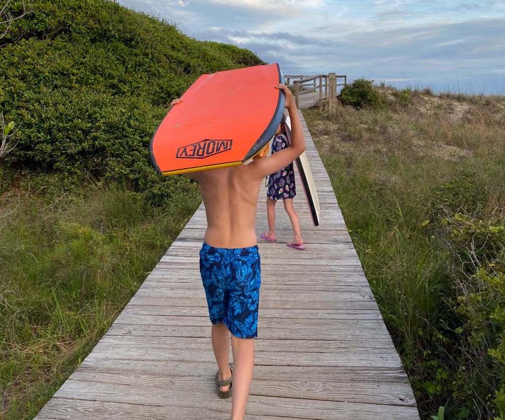 Kids carry boogie boards along a board walk on a South Carolina island.