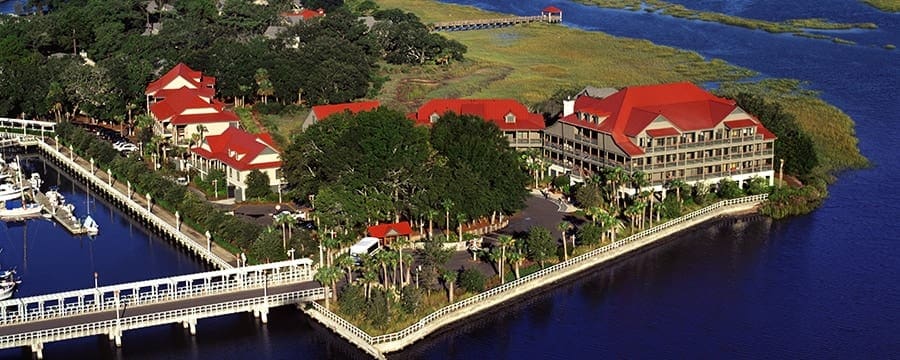 A view of the resort buildings for Disney’s Hilton Head Island Resort, featuring bright red roofs, from the water, with a full ocean view around the peninsula.