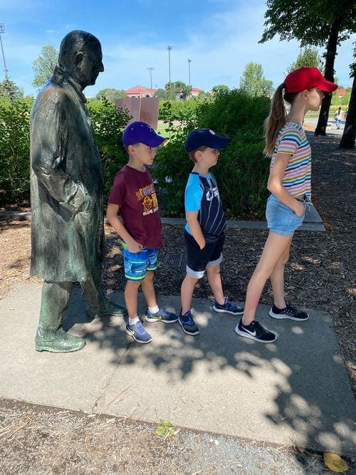 Three kids line up in front of a statue at the Minneapolis Sculpture Garden, one of the best things to do in Minneapolis with kids.