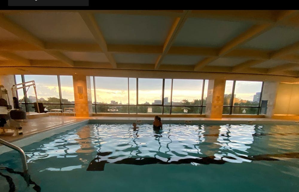 The indoor pool at the Four Seasons Hotel Boston with huge windows letting in the evening sun.