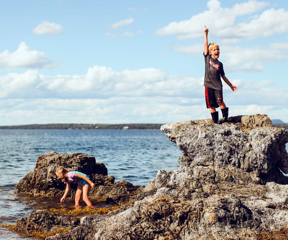 Two young children explore tidepools while explore Bar Harbor, Maine.