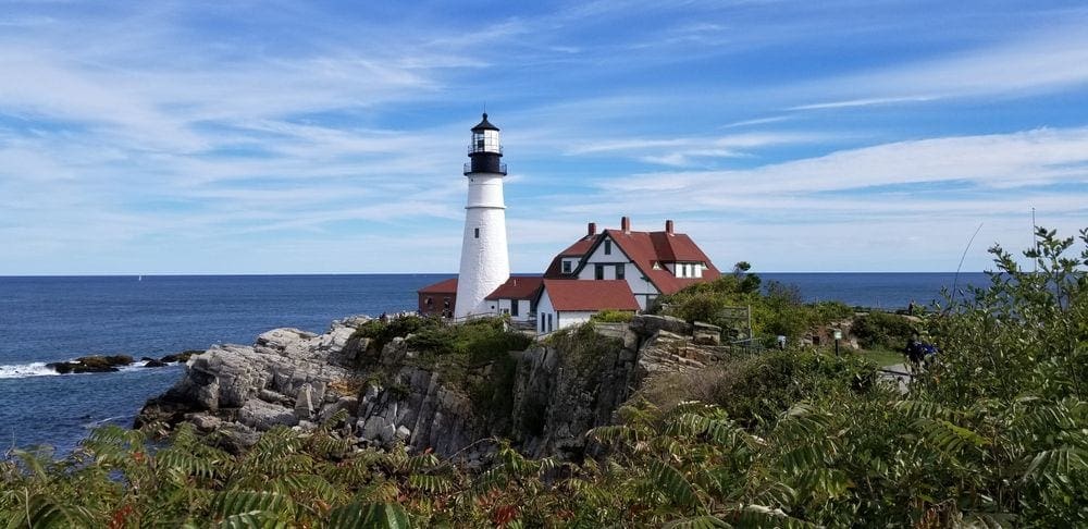 A lighthouse with a keeper's house stand charmingly along a shore near Portland, one of the best places to visit in Maine with kids.
