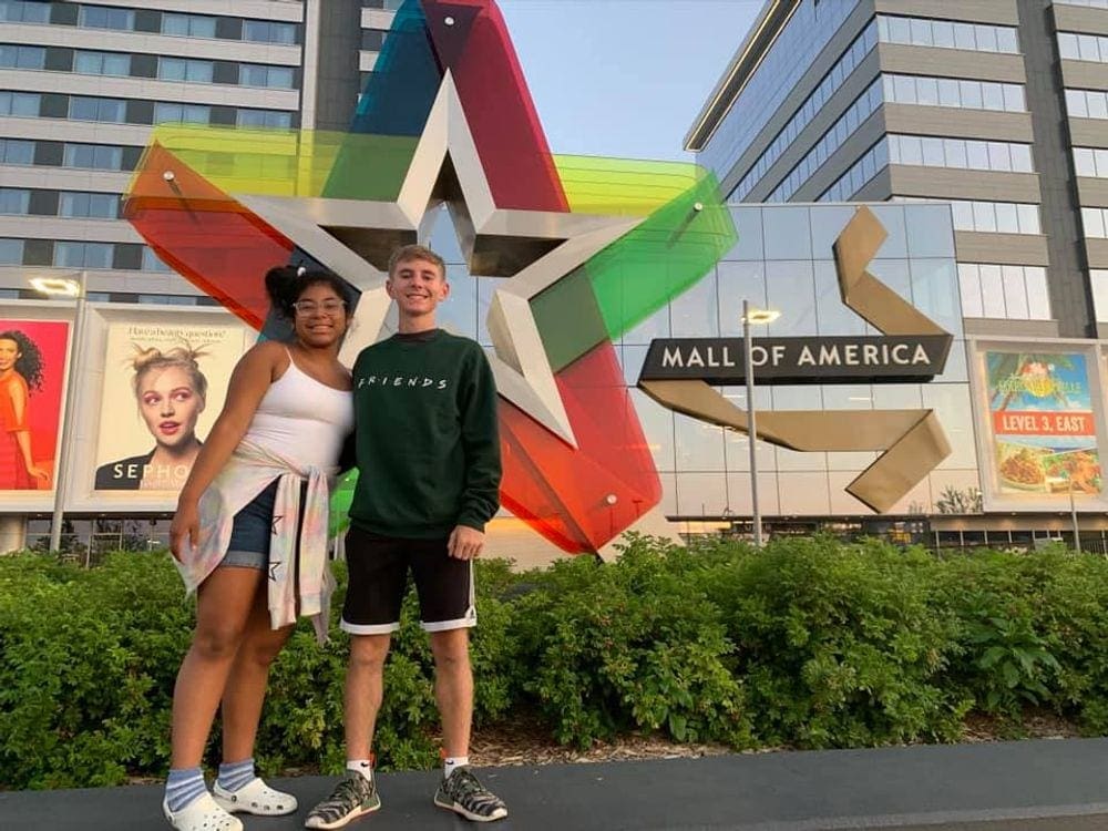 Two kids stand in front of the outdoor sign for the Mall of America, one of the best things to do in Minneapolis with kids.