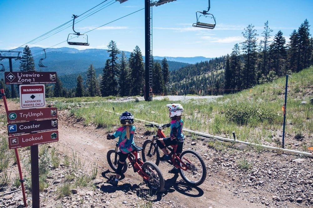 Two kids with helments ride mountain bikes along a rock trail at Northstar California Resort Lake Tahoe.