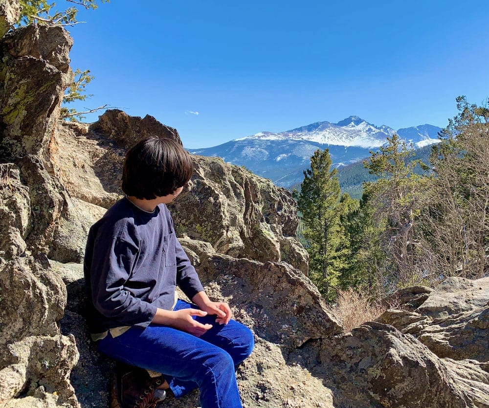 A young boy looks over a sweeping view of Rocky Mountain National Park, one of the best places to visit in Colorado with kids.