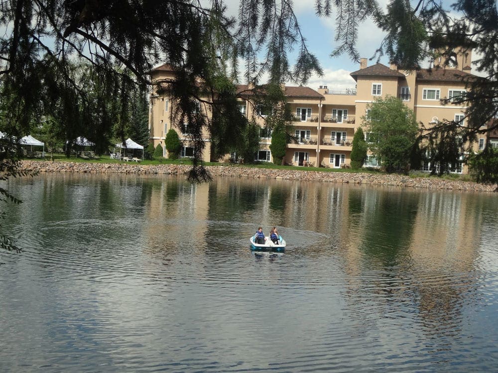 Two kids paddle along the lake while exploring the grounds of the Broadmoor, one of the best things to do in Colorado Springs with kids.