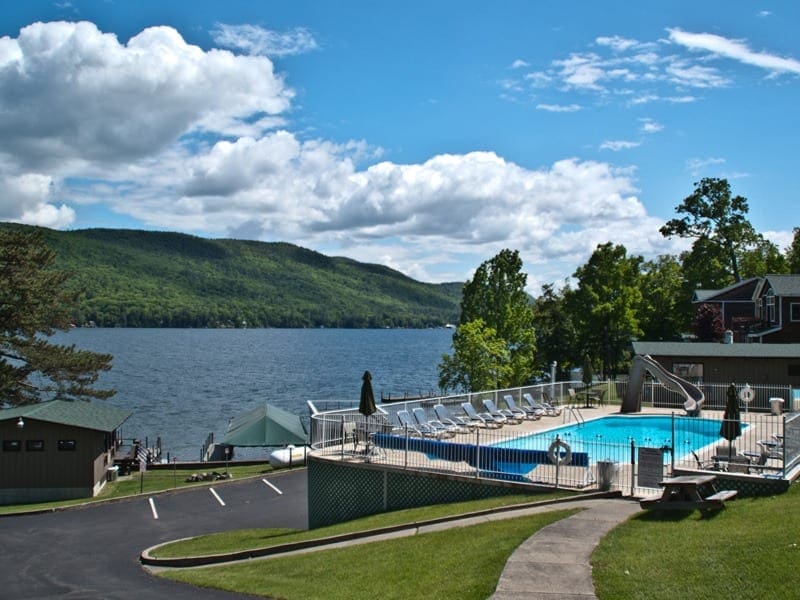 A sidewalk leads to the outdoor pool at Sun Castle Resort, with the lake in the distance.