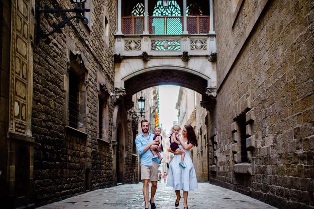 A family of four stands in a historic street within the Gothic Quarter of Barcelona.