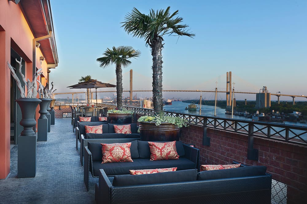 The well-furnished terrace of the Bohemian Hotel Savannah Riverfront, Autograph Collection, with views of Savannah in the distance.