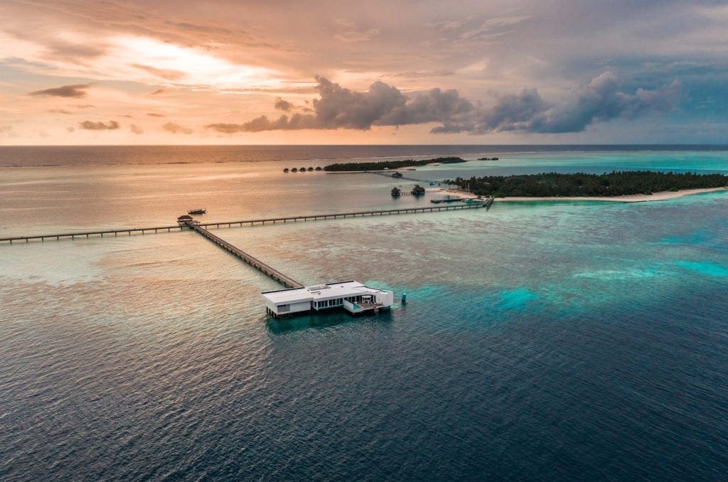 An aerial view of the Conrad Maldives Rangali Island at sunset, one of the best family hotels in the Maldives.