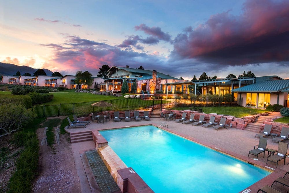 The pool and surrounding hotel buildings during sunset at Garden of the Gods Resort and Club, one of the best hotels in Colorado Springs for families.