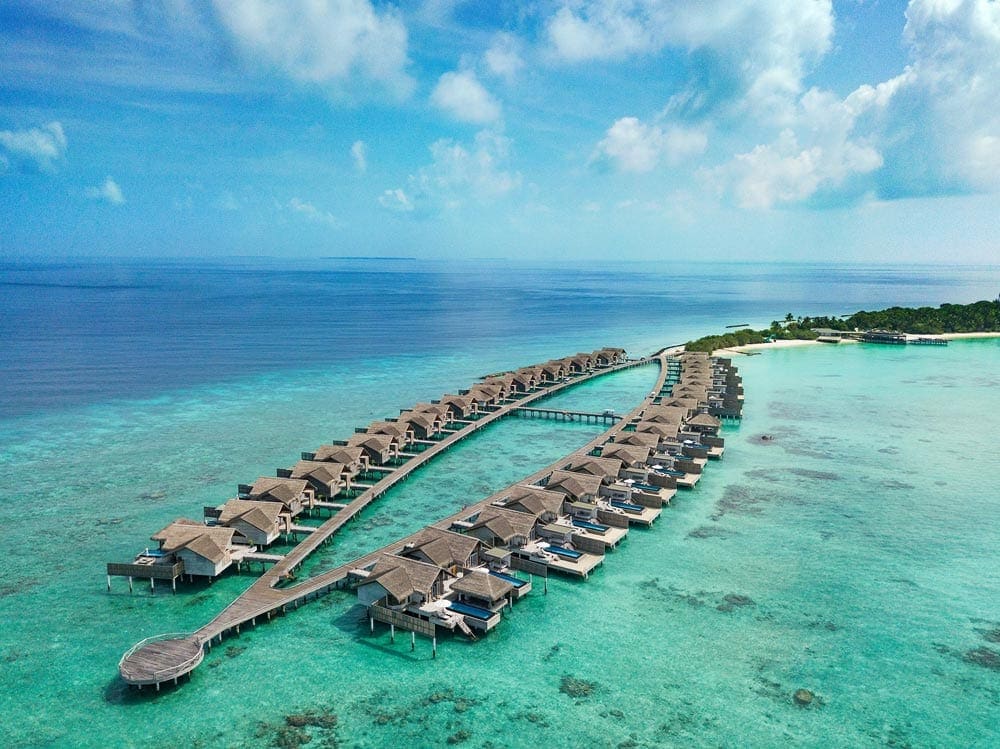 An aerial view of the two rows of over-water bungalows at the Hotel Fairmont Maldives - Sirru Fen Fushi, one of the best family hotels in the Maldives.
