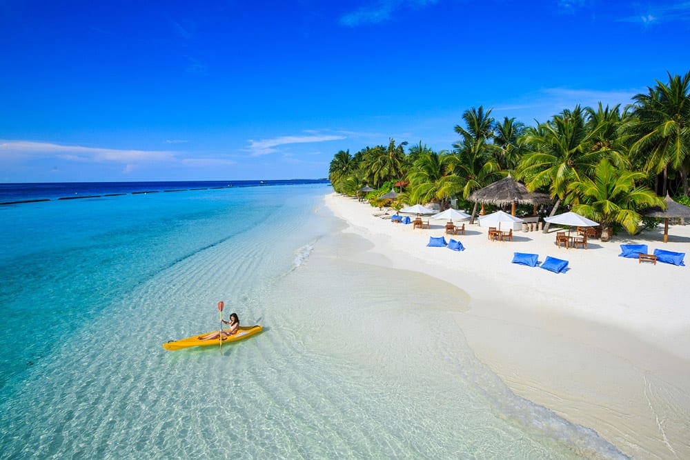 A lone kayaker enjoys the water off-shore from the Kurumba Maldives, one of the best family hotels in the Maldives.
