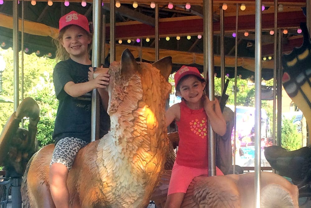 Two kids ride the Rose Kennedy Greenway Carousel, one of the best things to do in Boston with kids.