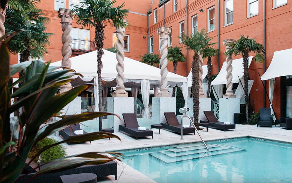 The outdoor pool with posh loungers and cabanas at the Mansion on Forsyth Park, Autograph Collection, one of the best hotels in Savannah for families.