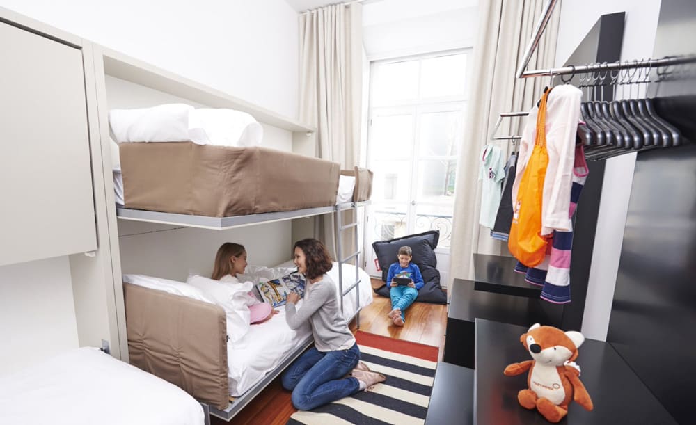 A mom and daughter sit together in a bunk bed room at Martinhal Lisbon Chiado Family Suites, one of the best hotels in Lisbon for families.