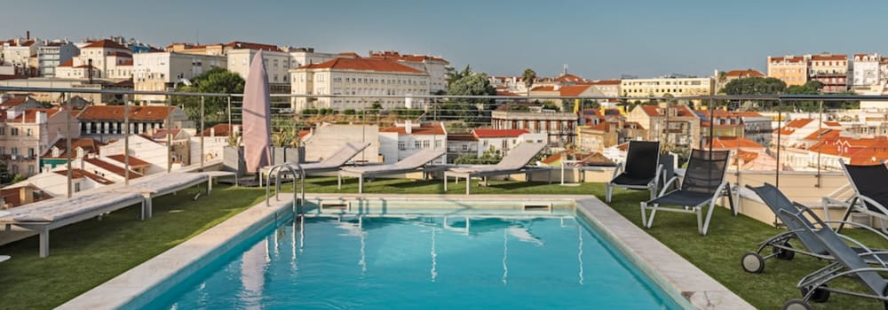 The outdoor pool, flanked with pool loungers, on the roof of NH Collection Lisboa Liberdade.