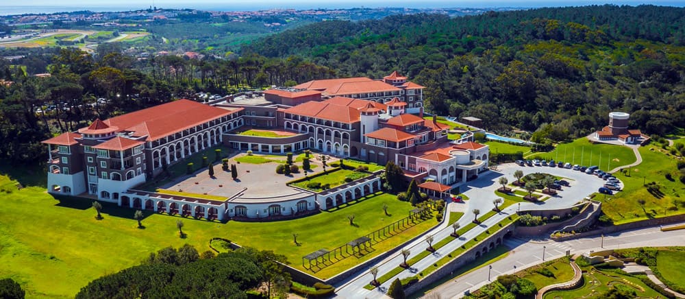 An aerial view of the Penha Longa Resort, featuring a red-tiled roof and green grass.