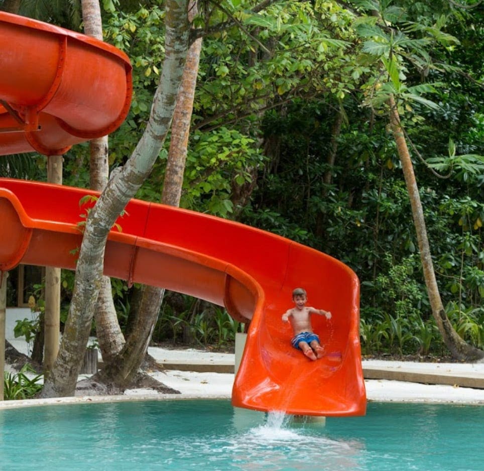 A young boy shoots down a big red slide at Soneva Fushi, one of the best family hotels in the Maldives.